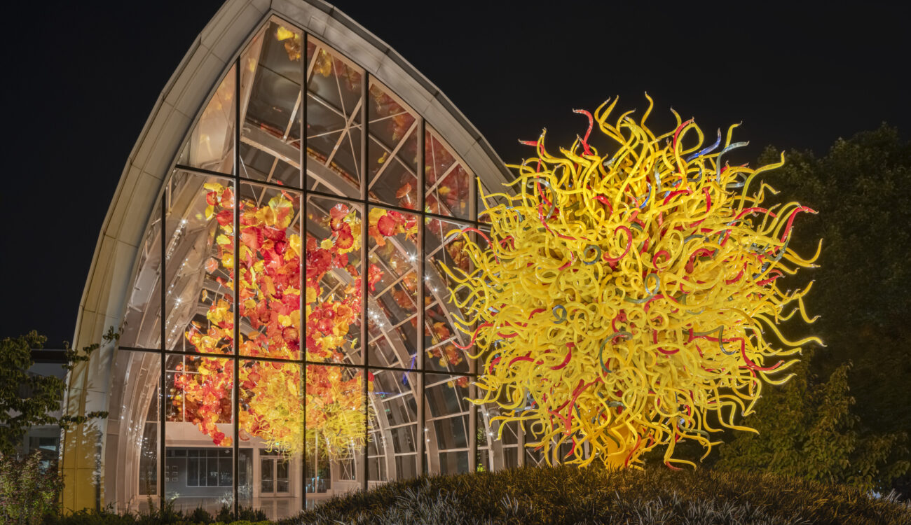 Chihuly Garden and Glass glasshouse with colorful sculpture at night